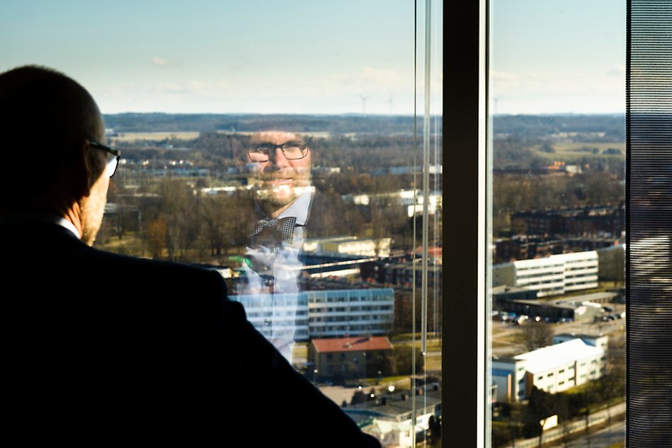 Man reflected in a window with a view of a town