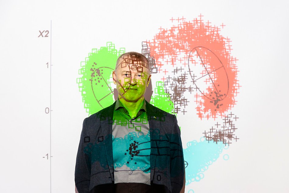Man standing in front of a white wall, a graph is projected on him