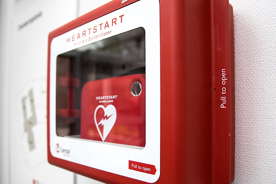 A defibrilator in a glass case with red corners. Photo.