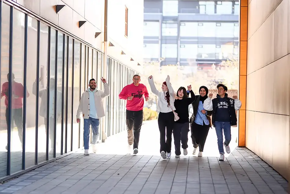 Six people running towards the camera, waving. Photo.