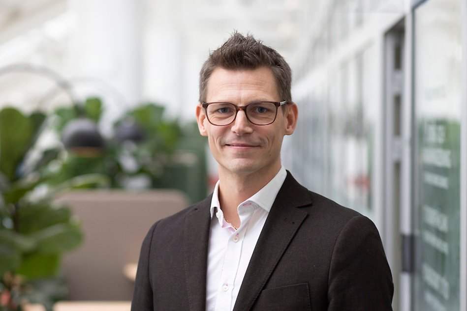 Man with short dark hair and glasses is looking into the camera. Photo.