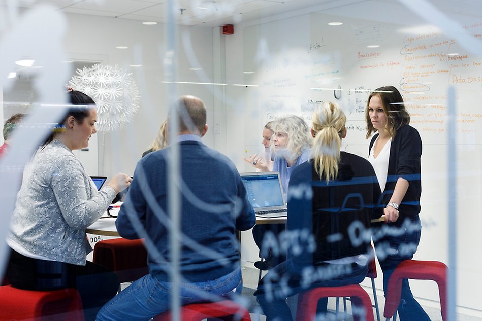 En grupp personer runt ett bord diskuterar med varandra. Foto.