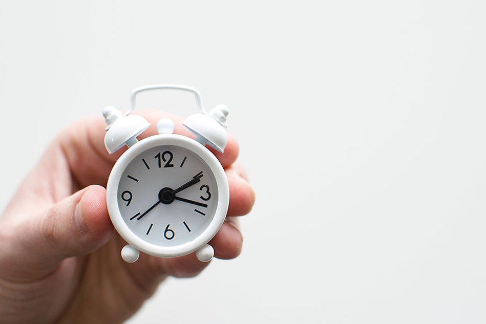 A hand holding a clock.