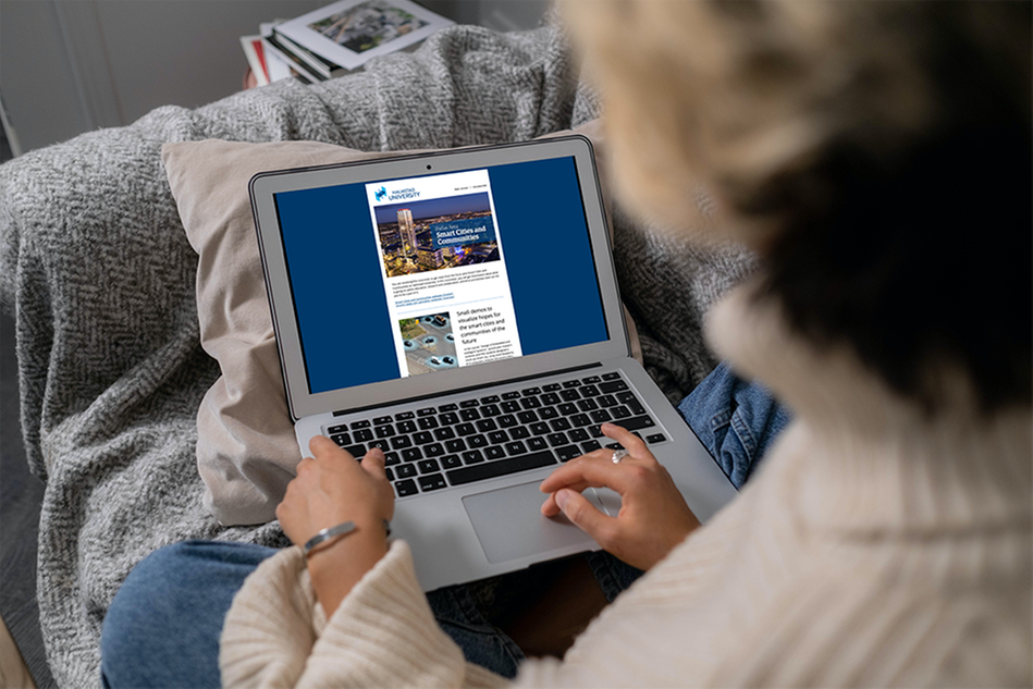 A person reading a newsletter on a laptop. Photograph.