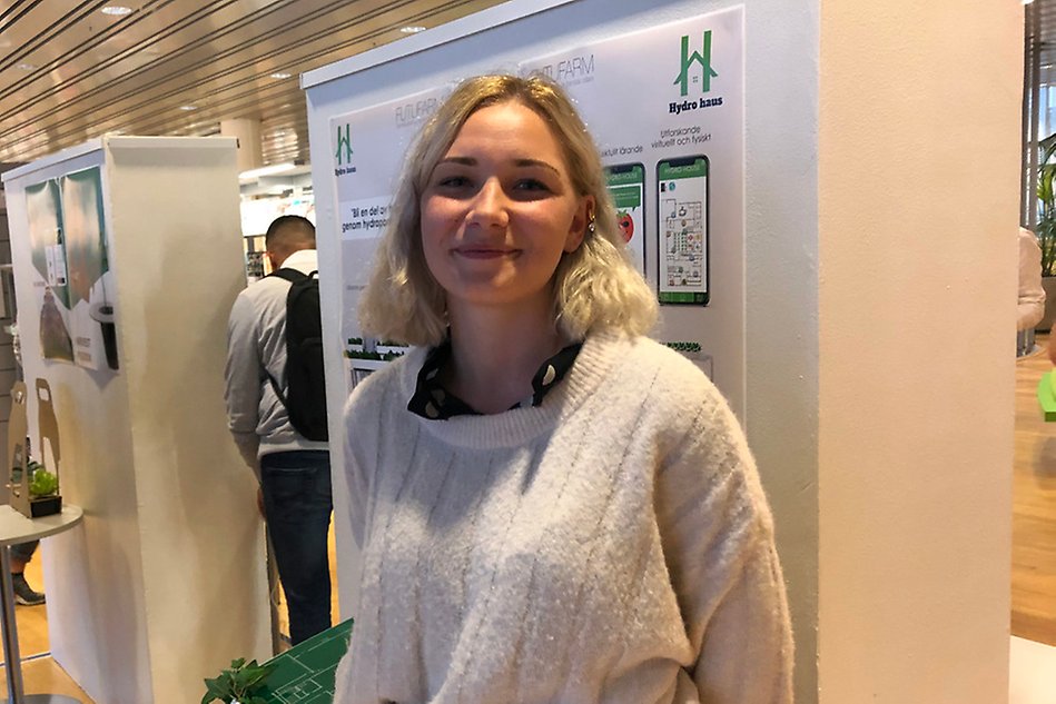 En ung, blond kvinna vid en monter. Foto.