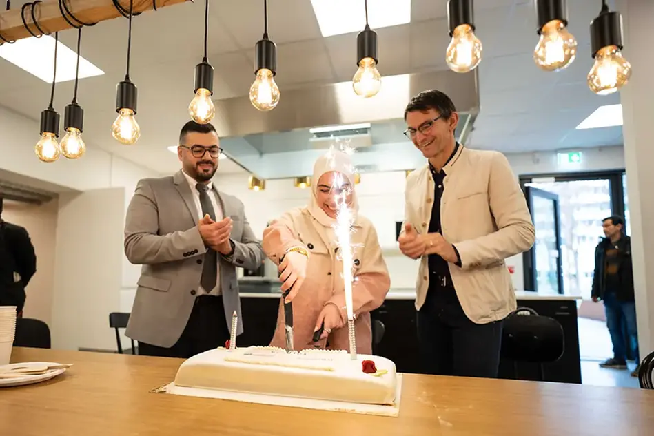 Henrik Barth, Ghazal Zalkat and Mohamed Barhamje celebrate a milestone in the PLOUTOS project with cake. Photo