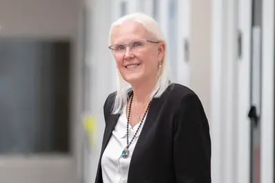 Woman with long hair and dark jacket looks into the camera. Photo