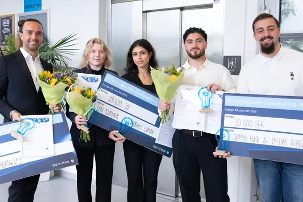 Fem finklädda studenter ler mot kameran samtidigt som de håller i diplom, värdecheck och statyett.