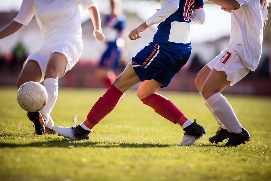En grupp spelar fotboll på en fotbollsplan.