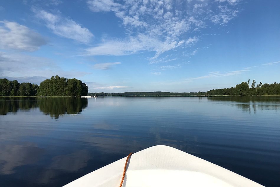 The front of a boat and a mirror-shiny water surface. Photo.