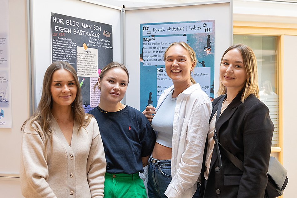 Fyra studenter står framför sin monter och ler mot kameran. Foto.