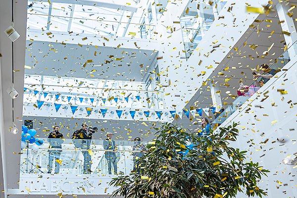 Golden confetti in the air, green plant and people in the background on a balcony. Photo.