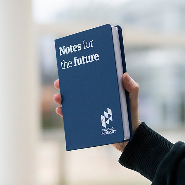 En hand håller upp en mörkblå bok med texten ”Notes for the future” i vitt. Foto.