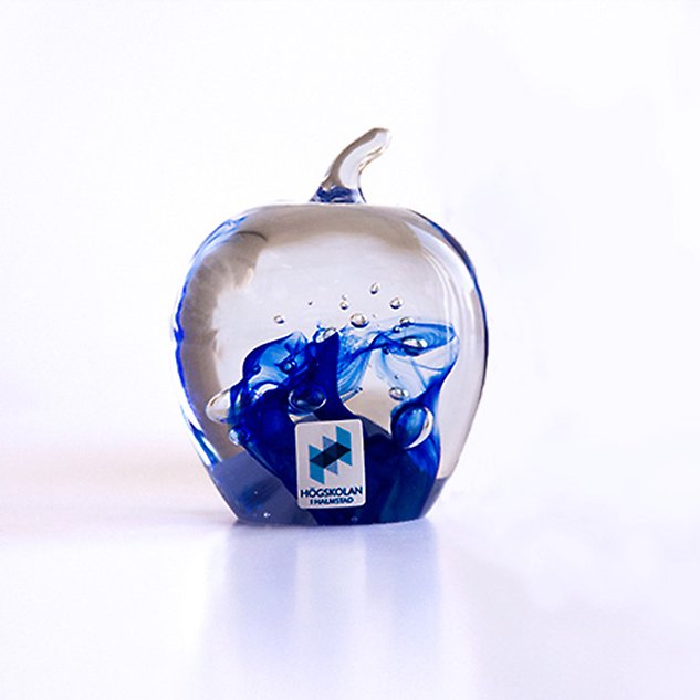 Glaskonst i form av ett äpple med blått mönster inuti. Foto. 