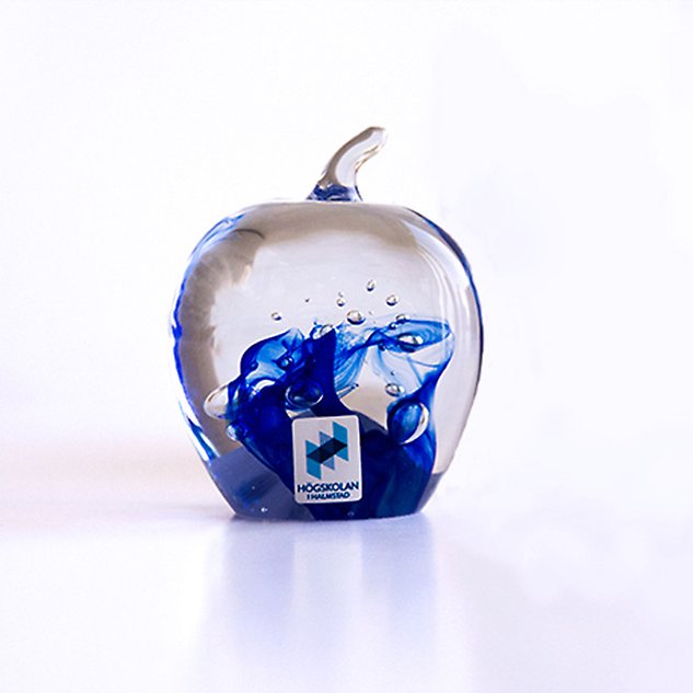 Glass art in the shape of an apple with a blue pattern inside. Photo.