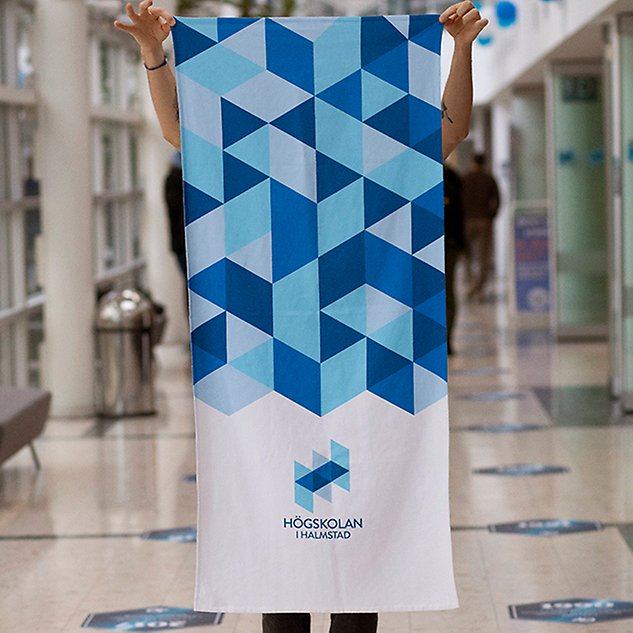 A person holds up a piece of patterned fabric in front of them. Photo.