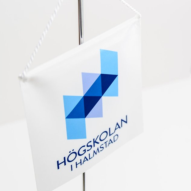 En vit flagga med Högskolans logotyp på. Foto. 