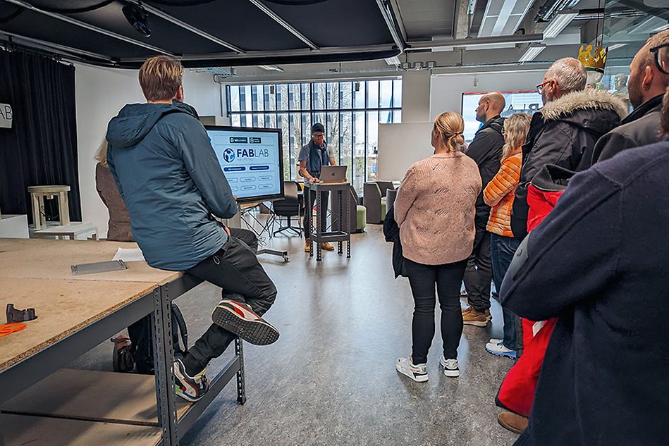 A group of people watch as a person presents at a computer.