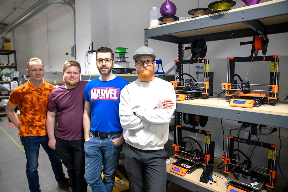 Fyra personer som står bredvid 3D-skrivare. Foto.