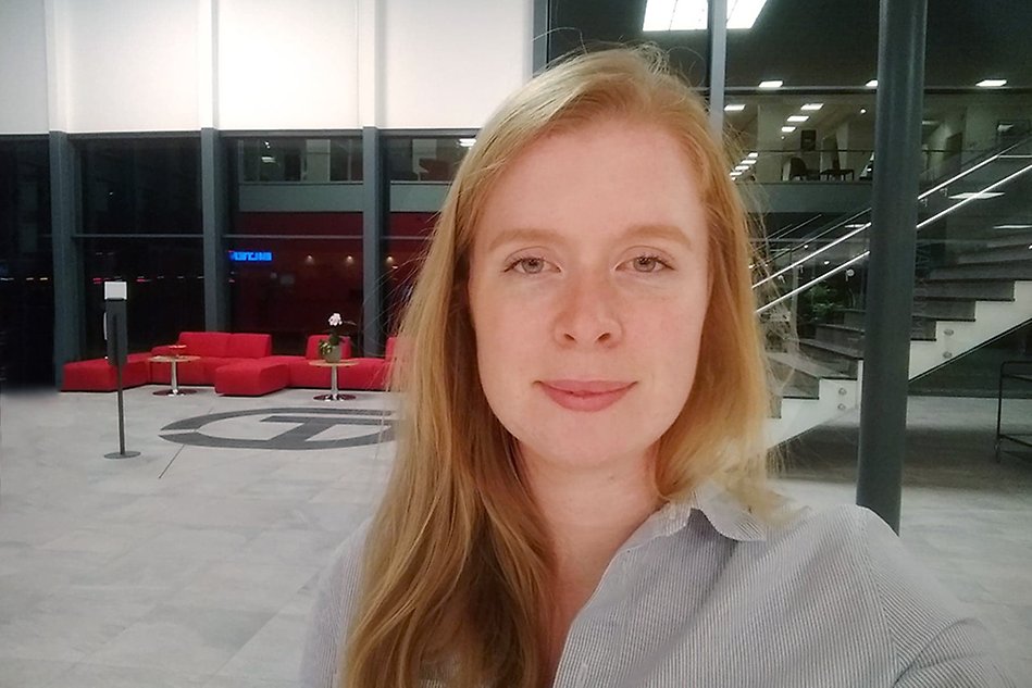 Person in front of a an open space with a staricase and a red couch.