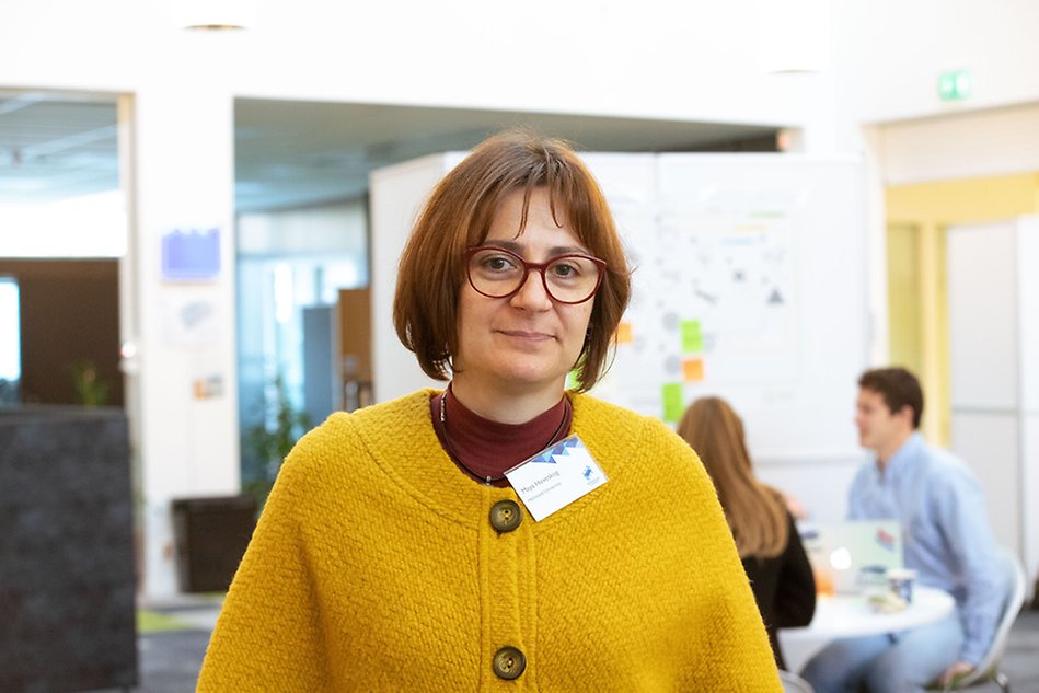 Portrait of a person with dark hair and wearing a yellow cardigan.