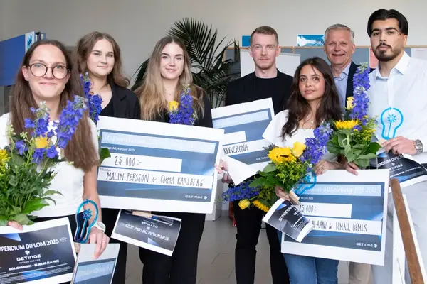 Sex studenter och en näringslivsrepresentant ler mot kameran. Studenter håller i värdecheckar, blommor och statyetter. Foto.