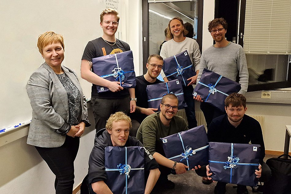 Students holding their prizes and Programme Director posing with a smile. Photo.