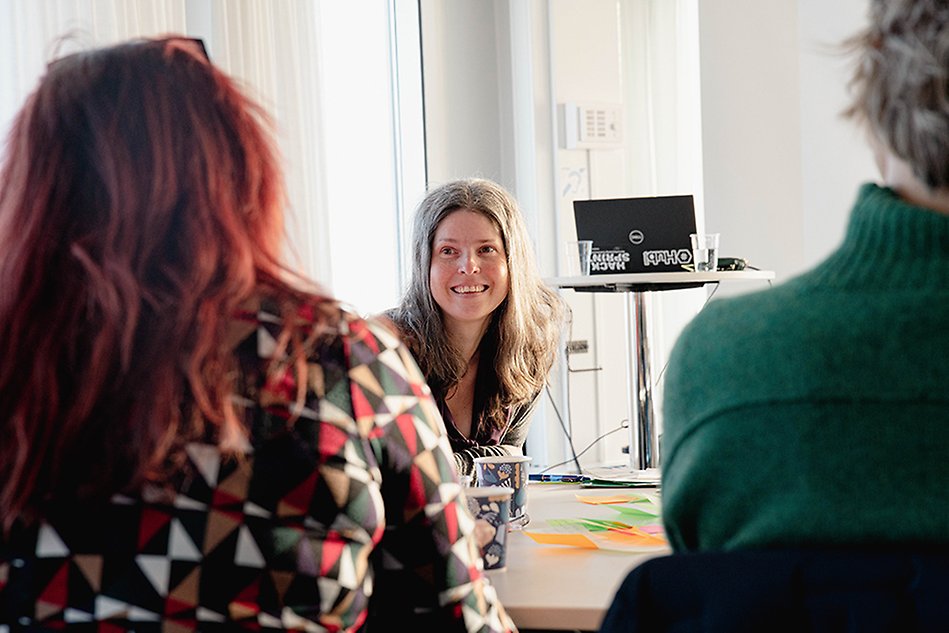 Personer som sitter och pratar med varandra. En person bakifrån och en framifrån. Foto.