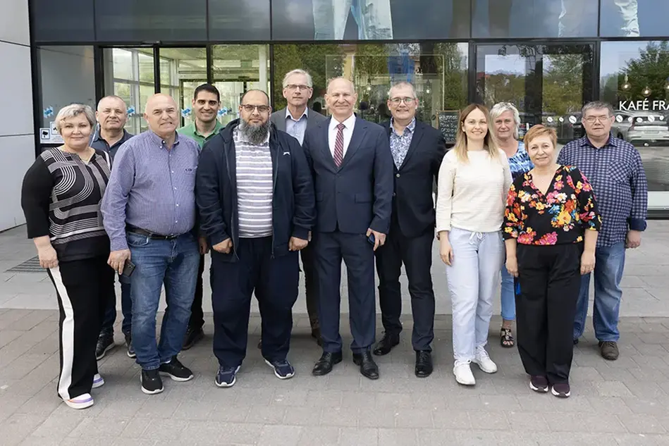 Bild på en grupp män och kvinnor framför en entré. De ler mot kameran.