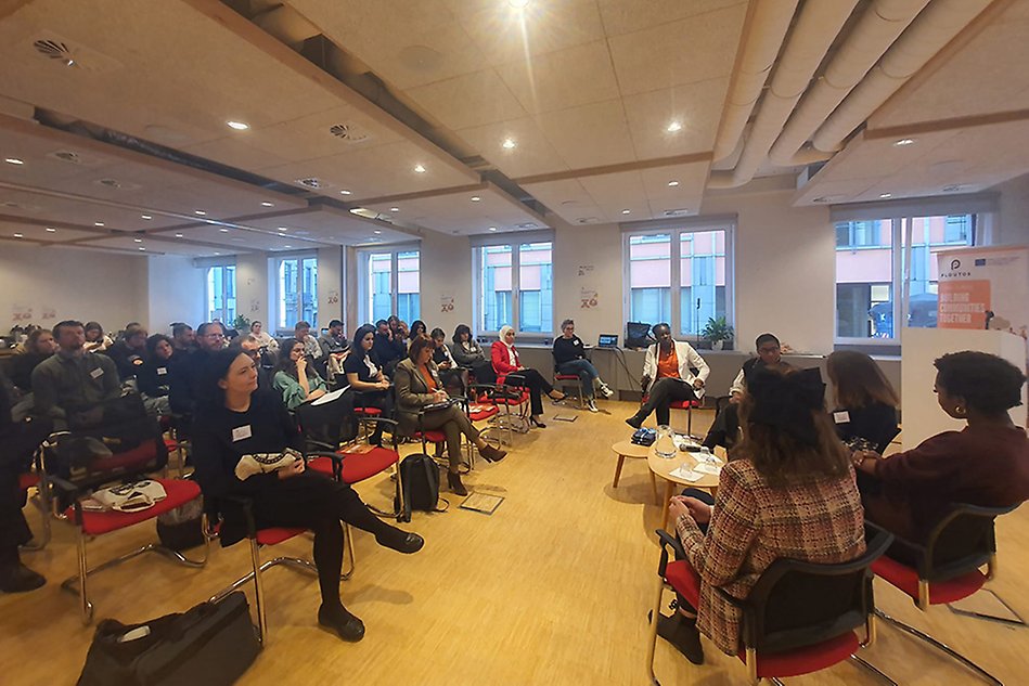 A large group of adults sitting in chairs in a classroom like environment. Photo.