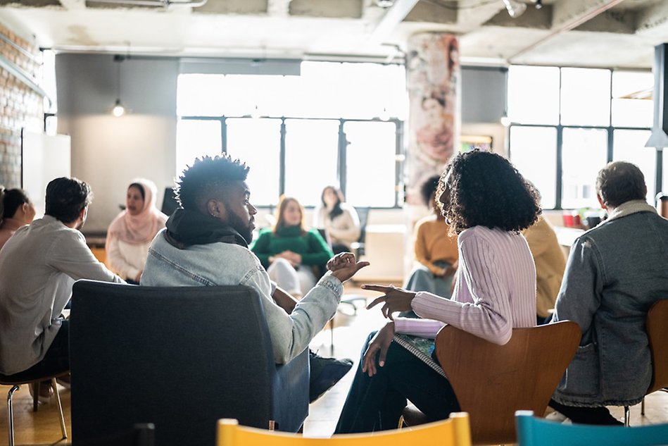 Several people in a room talking. Photo.