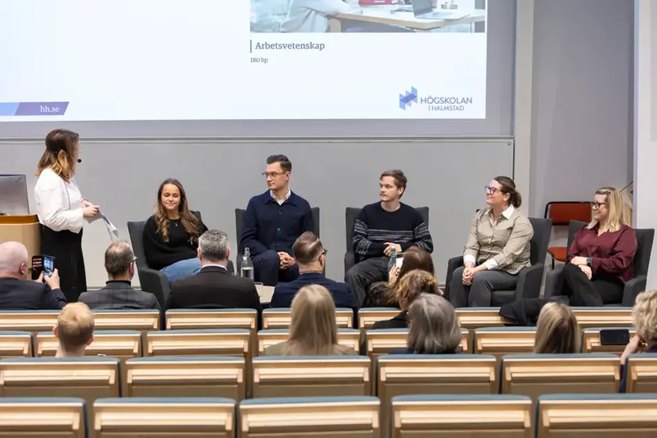 Fem personer sitter och samtalar framför en publik. Foto