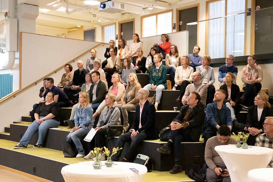 Många människor som sitter i en gradäng och är publik. Foto.