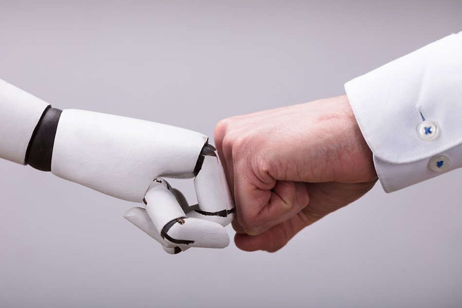 A robothand and a human hand makes a fist-bump.