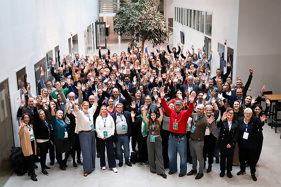 A large group of people standing in an open space at campus, cheering. Photo.