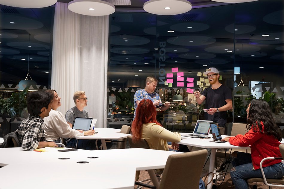 En grupp personer i ett konferensrum ler medan de håller i en workshop. Foto.