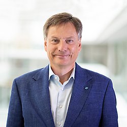 A portrait of a man in white shirt and blue jacket looking into the camera. Photo.