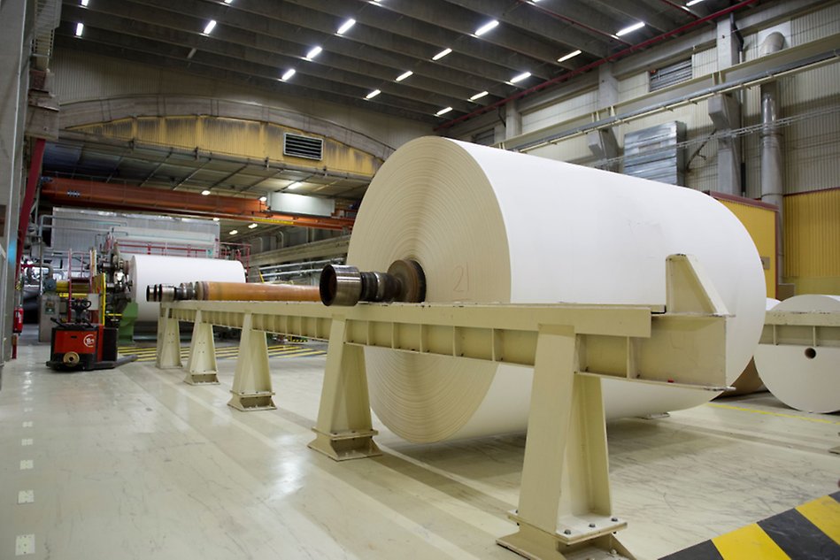 Big roll of paper on top of a machine at a paper mill.