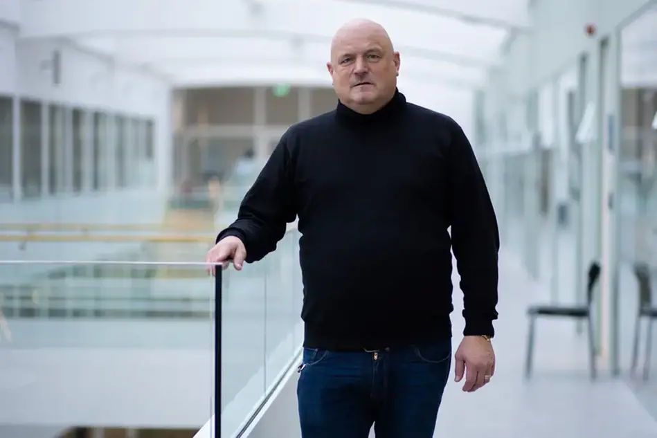 A man in a black sweater is standing on a balcony.