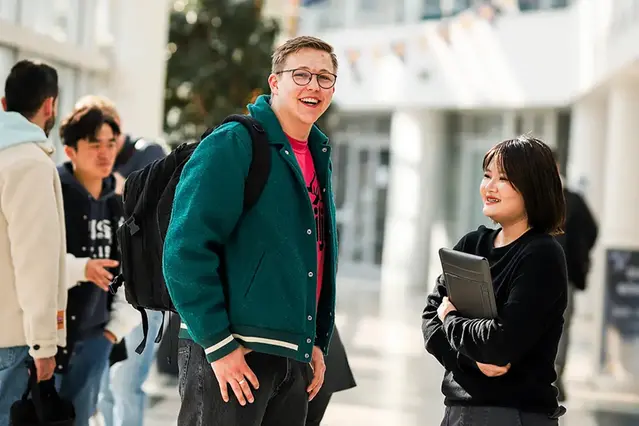 Two persons conversating in a corridor at campus. Photo.