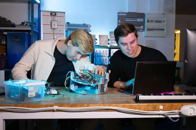 Two students are working on a prototype in an electronics lab. Photo.