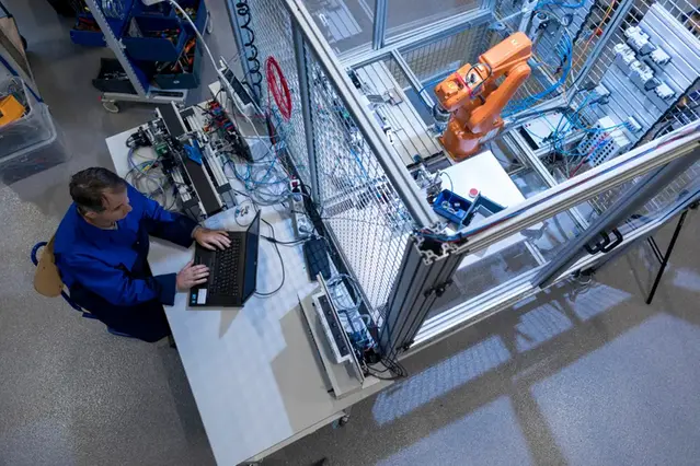 A student sits at a laptop in an electronics lab. Photo.