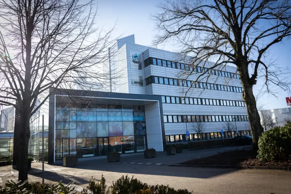 En byggnad med många fönster och träd framför sig.