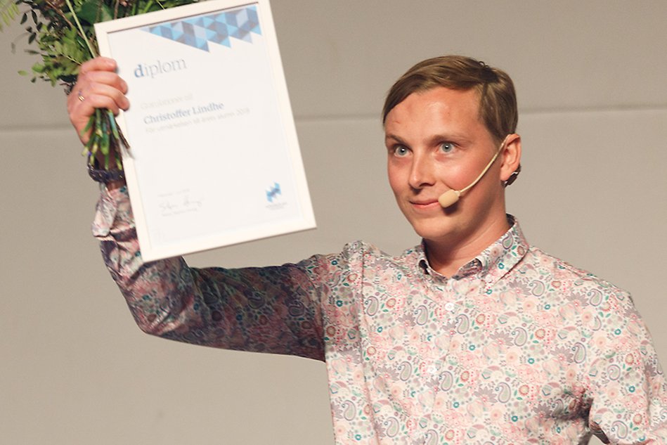 Man håller upp ett diplom. Foto.