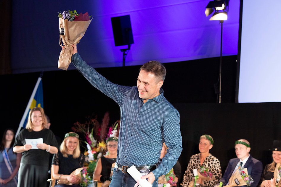 A person wearing a shirt, holding up an arm in a celebratory gesture. 