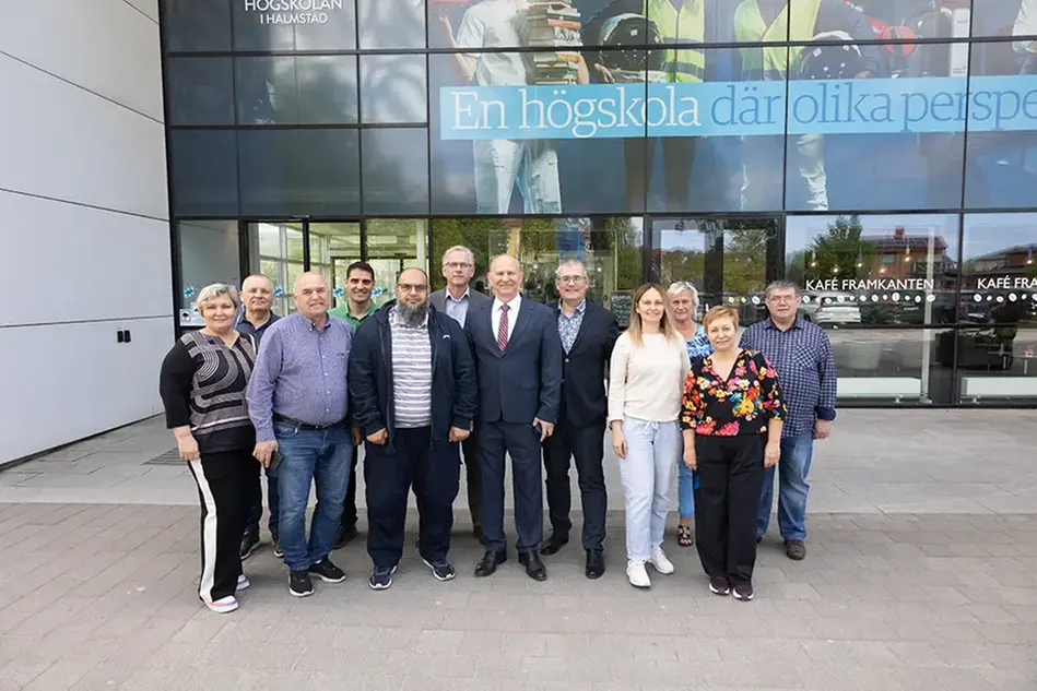 En grupp människor står framför Högskolans entré. Foto.