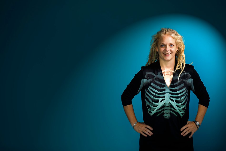 En person i en svart tröja med skelettryck. Blå bakgrund. Foto.