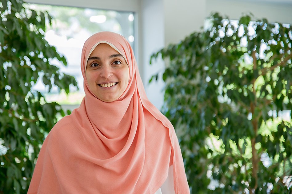 Woman wearing a pink hijab smiling at the camera. Photo.
