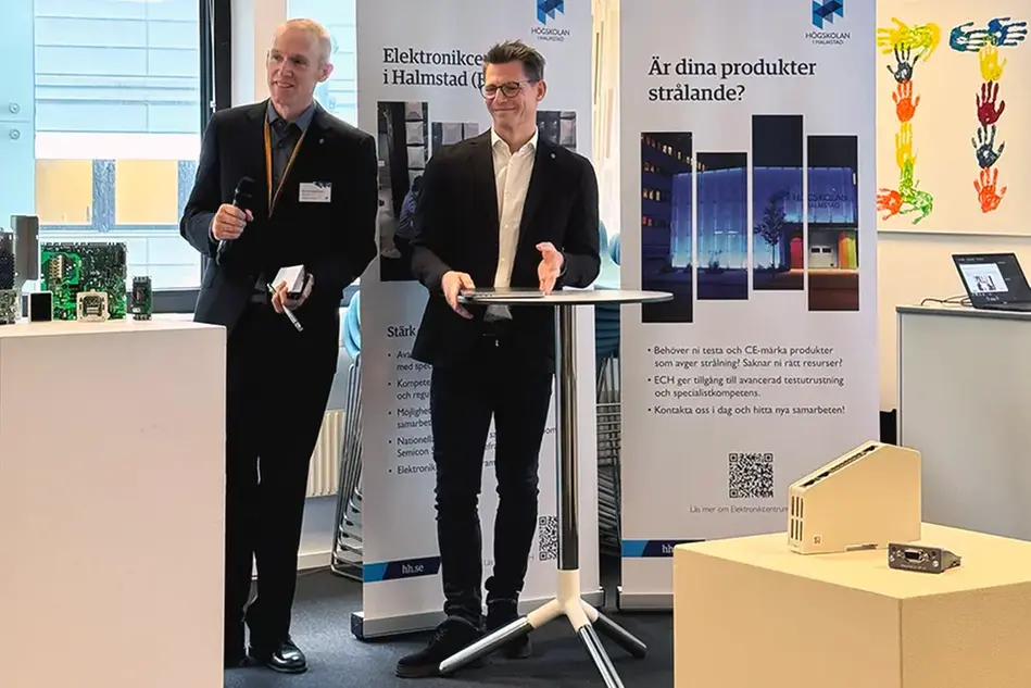 Två män i kostym står framför två roll-ups. Foto.