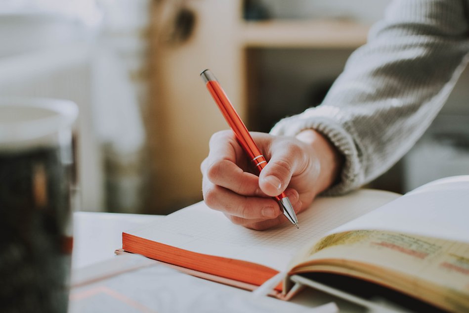 A person writing in a notebook. Photo.